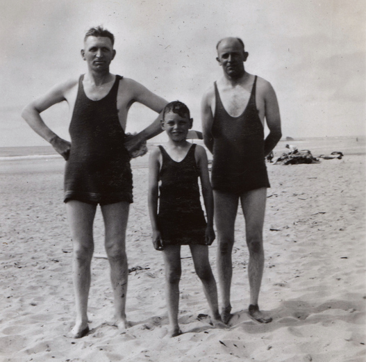 Three swimmers standing on a beach