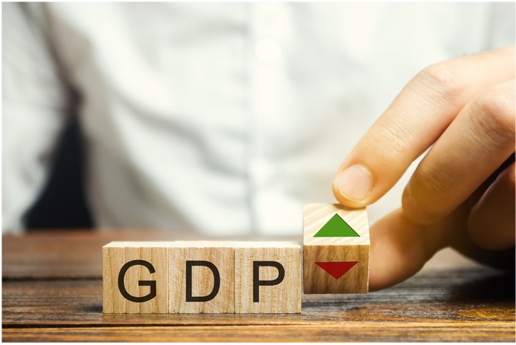 Image of block letters spelling out GDP and a hand flipping a green arrow block to a red arrow block