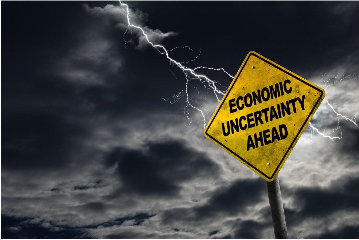 Signs that reads "Economic Uncertainty Ahead" in front of a stormy sky