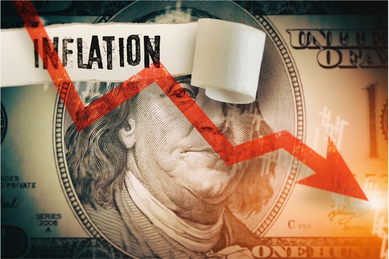 Downward chart overlaid on a hundred dollar bill being ripped to reveal the word inflation