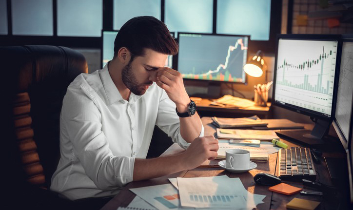 Office worker sitting at his desk with a stressed expression.