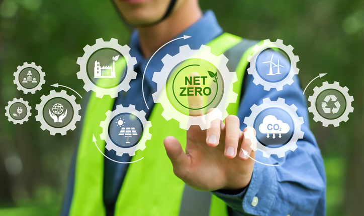 Construction worker tapping on a gear that says Net Zero