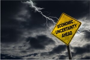 black and yellow street sign that reads "Economic uncertainty ahead"