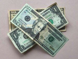 Pile of money with a ten-dollar bill on the bottom, a one-dollar bill on top and a twenty-dollar bill on the very top