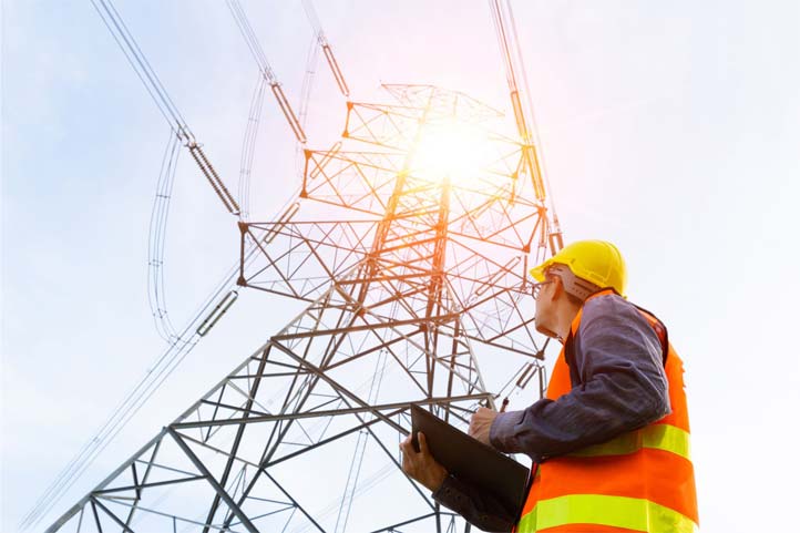 A man looking up at electrical lines and taking notes