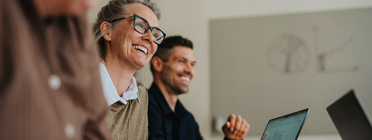Woman with glasses laughs at colleague's joke